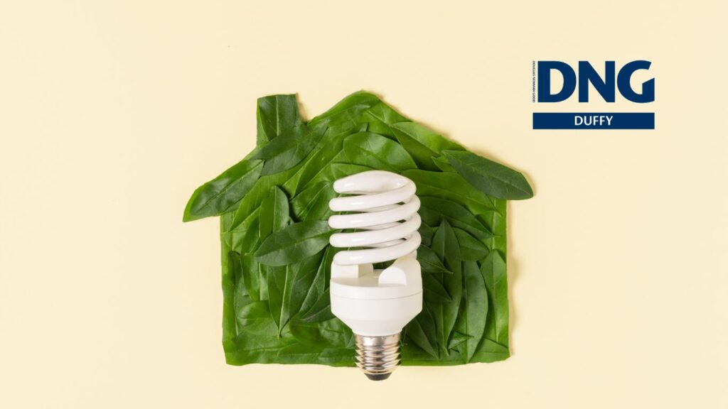 long life lightbulb in front of a picture of a house made from leaves