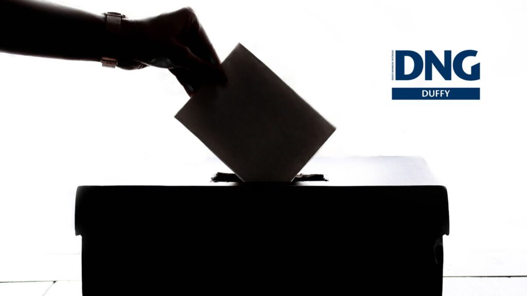 silhouette of voter placing a vote into a ballot box